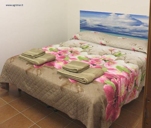 Una cama con flores rosas y toallas. en Agrimar, en Magliano Romano