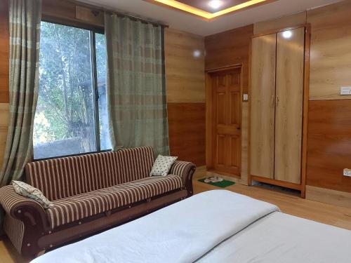 um quarto com um sofá, uma cama e uma janela em Flora Inn Skardu em Skardu