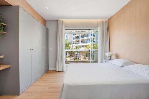 a bedroom with a large white bed and a window at Cobertura Duplex Vista Mar - Ofurô - 4 suítes in Bombinhas
