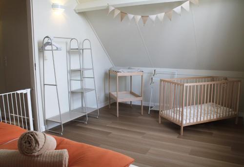a room with a crib and a table and shelves at Design Idyll am Wasser in Breskens Haus mit Steg, Lounge, E Ladestation inklusive, 3 Schlafzimmer und 2 WCs in Breskens