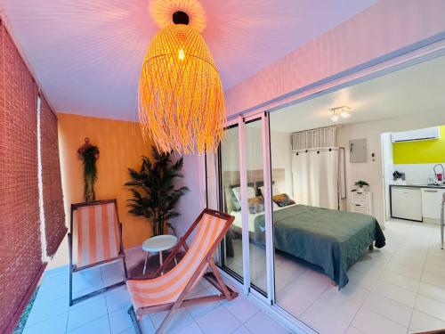 a bedroom with a bed and a chandelier at Superbe Studio Ultra COSY à 2 min de la PLAGE in Sainte-Anne