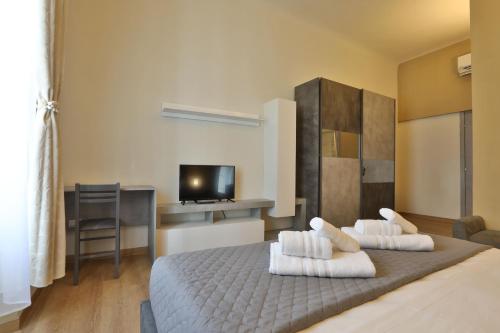 een slaapkamer met een bed met witte kussens en een televisie bij Morina Rooms in Trieste