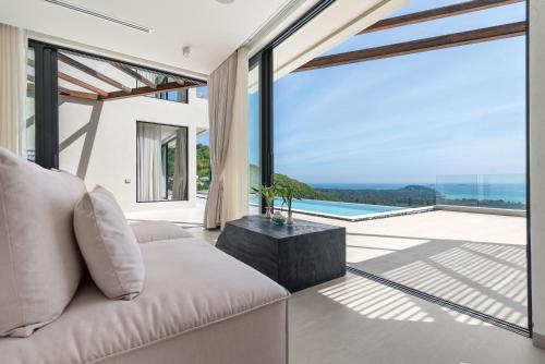 a living room with a couch and a large window at Sea Breeze Villa in Taling Ngam Beach