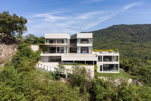 a house on the side of a hill with trees at Sea Breeze Villa in Amphoe Koh Samui