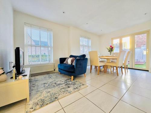 a living room with a blue chair and a table at Modern 3-Bed plus Office - Walk to Bicester Village in Bicester