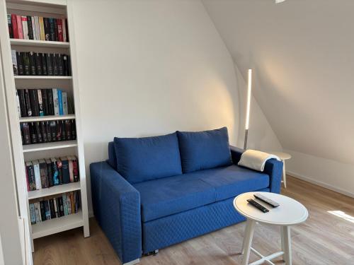ein blaues Sofa im Wohnzimmer mit einem Tisch in der Unterkunft Ruhiges und citynahes Dachgeschoss-Nest in Düsseldorf