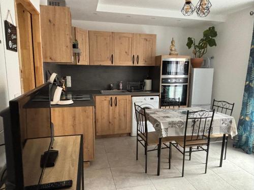 ニヨンにあるGîte cosy avec jardinのキッチン(木製キャビネット、テーブル、椅子付)