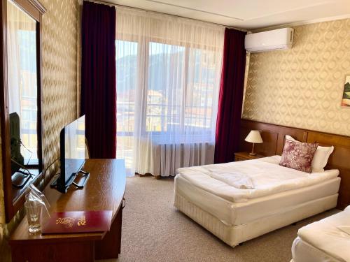 une chambre d'hôtel avec un lit, un bureau et une fenêtre dans l'établissement Хотел Елит Релакс, à Devin