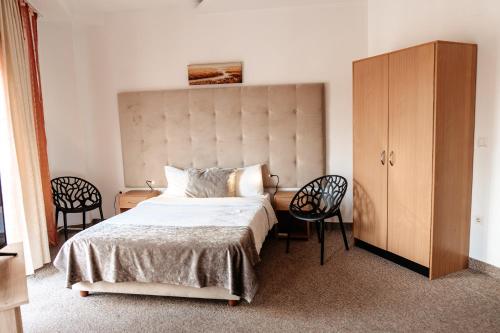 une chambre avec un grand lit et deux chaises dans l'établissement Hotel Strelitia, à Timişoara