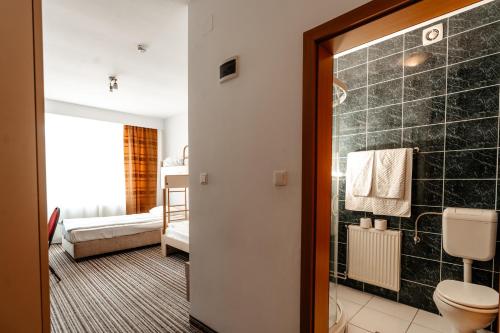 Un baño con inodoro y una gran pared de azulejos negros. en Hotel Strelitia, en Timisoara