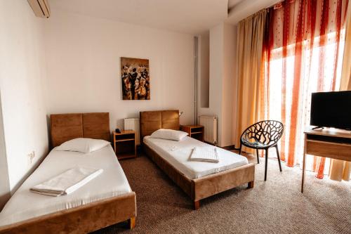 a room with two beds and a tv and a piano at Hotel Strelitia in Timişoara