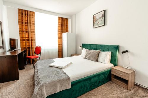 a bedroom with a large bed with a green headboard at Hotel Strelitia in Timişoara