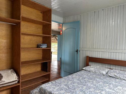 a bedroom with a bed and a book shelf at Aluguel para Temporada, Praia da Gamboa, Garopaba SC in Garopaba