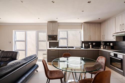 a kitchen with a glass table and chairs at 4-bedroom in the center of the Southern Suburbs! in Cape Town