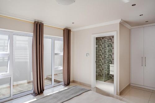a bedroom with white walls and large windows at 4-bedroom in the center of the Southern Suburbs! in Cape Town