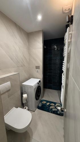 a bathroom with a toilet and a washing machine at C-Home in Pécs