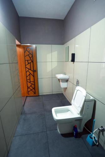 a bathroom with a toilet and a sink and a door at MoStays in Pāppinisseri