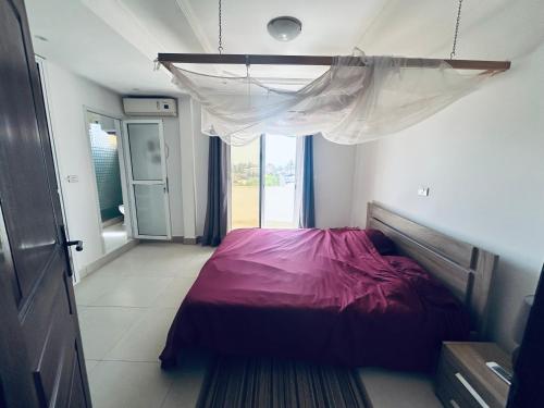 ein Schlafzimmer mit einem Bett mit einer lila Bettdecke in der Unterkunft Appartement vue sur la mer Almadies Dakar "Résidence les embruns" in Dakar