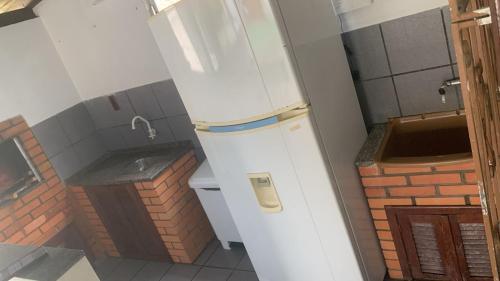 a white refrigerator in a bathroom with a brick wall at Pousada da Magia in Florianópolis
