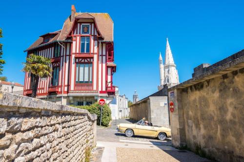 une voiture jaune garée devant un bâtiment rouge dans l'établissement Séjour prestige - vue mer et accès privé à l'océan, à Angoulins-sur-Mer