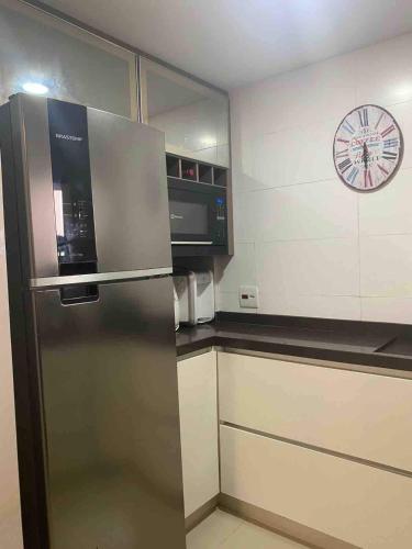 eine Küche mit einem Kühlschrank und einer Uhr an der Wand in der Unterkunft Confortável Apartamento em Angra dos Reis in Angra dos Reis