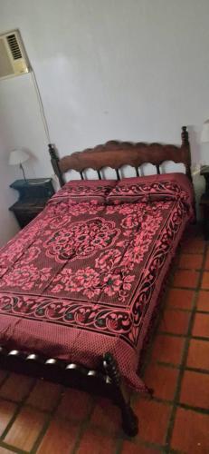 a bed with a red blanket on top of it at La Cañada in Colón