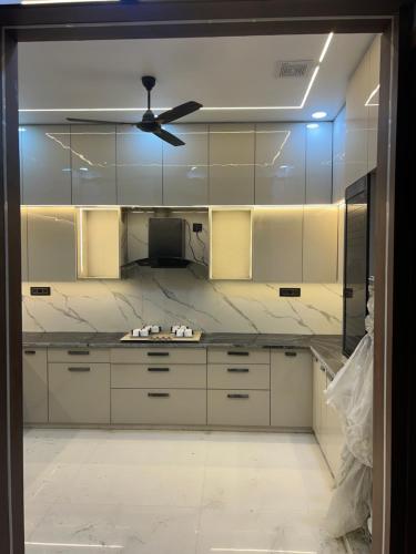 Il comprend une cuisine avec des placards blancs et un ventilateur de plafond. dans l'établissement Singhal Residency PG - RENT, à Greater Noida