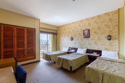 a hotel room with two beds and a couch at St George Hotel Cairo in Cairo