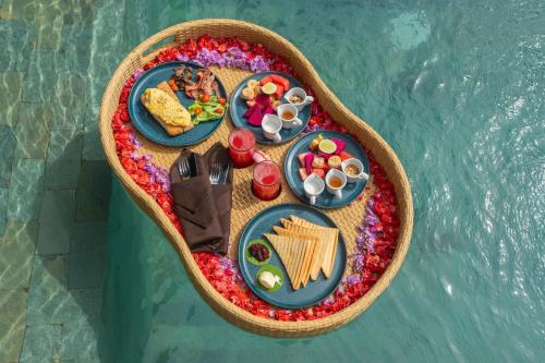 une table de nourriture dans une petite barque sur l'eau dans l'établissement Aksmi Suites & Villas, à Bedahulu