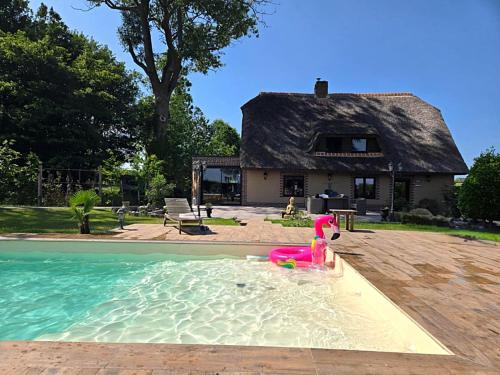 une piscine en face d'une maison dans l'établissement La Chaumière de Lilou, Havre de paix en campagne, à Merckeghem