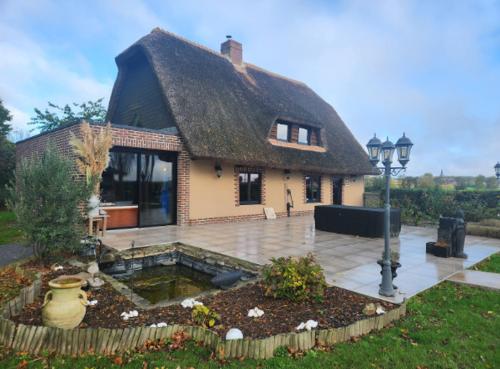 une petite maison avec un toit de chaume et une cour dans l'établissement La Chaumière de Lilou, Havre de paix en campagne, à Merckeghem
