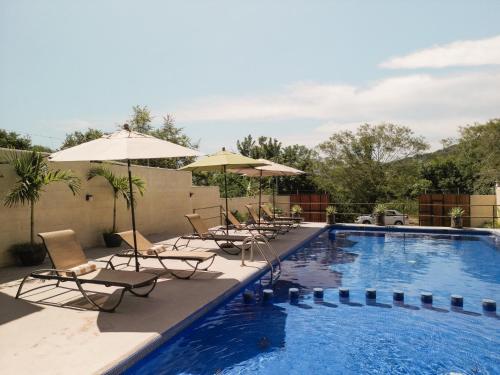 a swimming pool with lounge chairs and umbrellas at hotel isla Bonita in Zihuatanejo