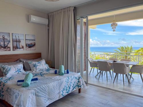 a bedroom with a bed and a dining room with a view at LAKAZ DEL VISTA - Luxurious new apartments with panoramic sea views, pool & garden retreat in Tamarin