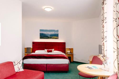a bedroom with a red bed and a red couch at Hotel Goisererhof in Bad Goisern