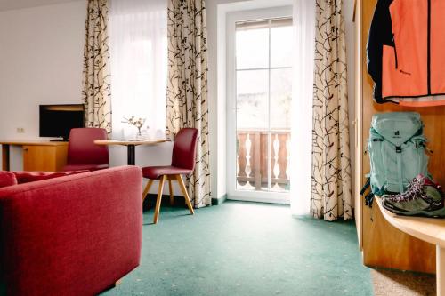 a living room with a red couch and a window at Hotel Goisererhof in Bad Goisern