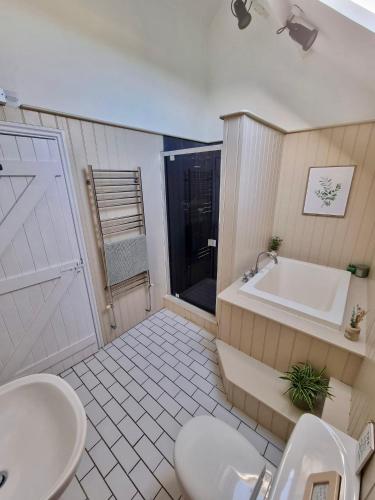 a bathroom with a tub and a toilet and a sink at The Piggery - North Wales Retreat - Wilde Retreats in Pwllheli