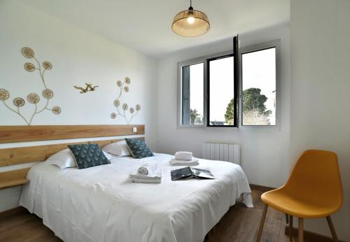 une chambre avec un lit blanc et une chaise jaune dans l'établissement La Plage du Petit Port, à Cancale