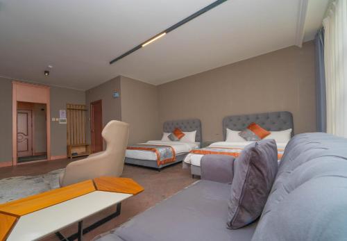 a hotel room with two beds and a couch at Amgun Hotel Ulaanbaatar in Ulaanbaatar