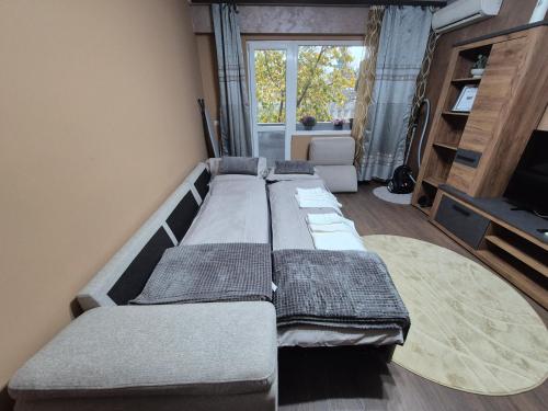 a large couch in a living room with a window at Апартамент Михаел in Vidin