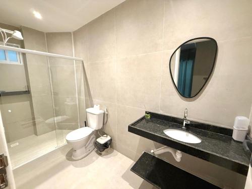 une salle de bain avec toilettes, lavabo et miroir dans l'établissement Apartamento mobiliado Beira-Mar, à Maragogi