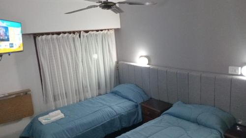 ein Hotelzimmer mit zwei Betten und einem Fernseher in der Unterkunft Gran Hotel Avenida in Villa Gesell