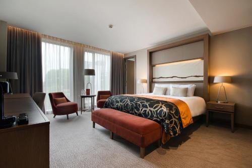 a large hotel room with a bed and a chair at Clayton Hotel Chiswick in London