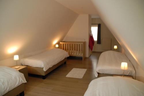 a attic room with two beds and a staircase at De Kruishoeve in De Haan