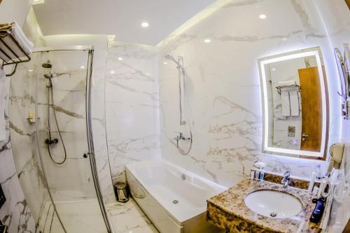 ein Badezimmer mit Badewanne, Waschbecken und Dusche in der Unterkunft Adisson Hotel Baku in Baku