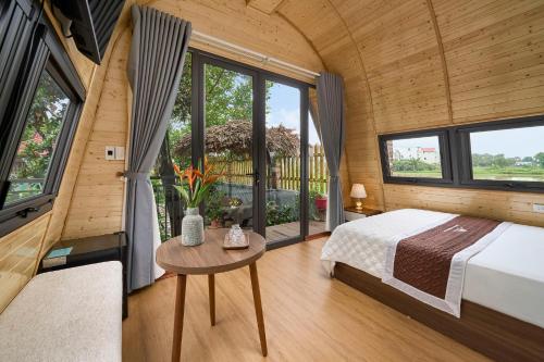 a bedroom in a tiny house with a bed and a table at TamCoc Moon An Bungalow & Cafe in Ninh Binh