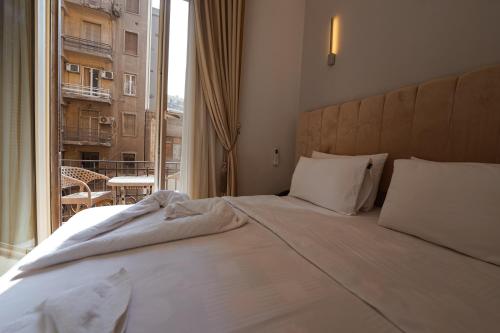 a bedroom with a large bed and a large window at KASTELLO hotel in Cairo