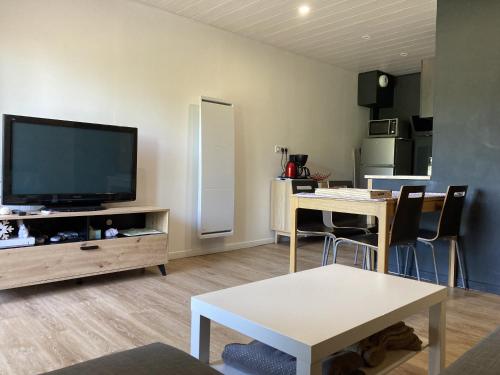 a living room with a flat screen tv and a table at Cocon montagne Rocher du Cerf in Le Lioran