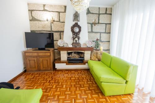 a living room with a green couch and a tv at Casa da Luisinha in Amarante