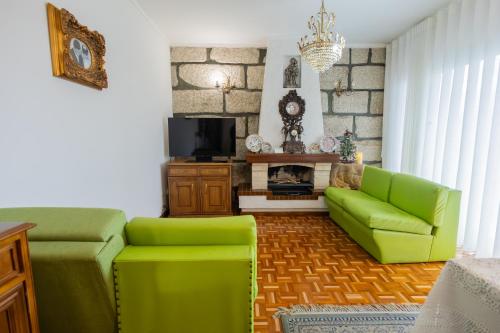 a living room with a green couch and a tv at Casa da Luisinha in Amarante
