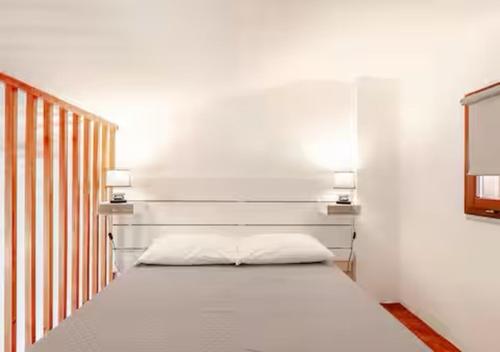 a bed in a white room with two lights at Alba Sea 27 in Casal Palocco